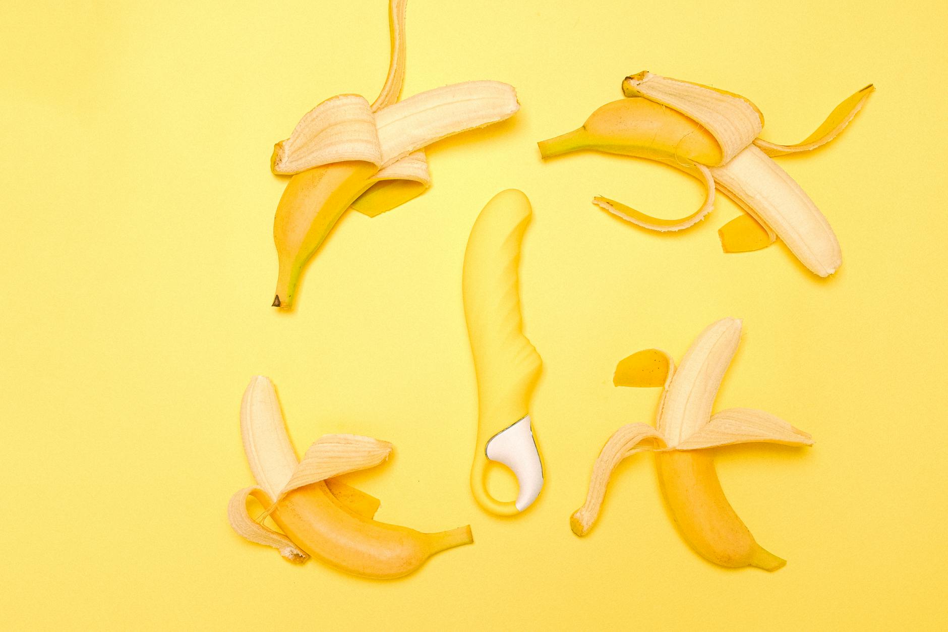 Yellow lemon vibrator surrounded by fresh fruit on a bright background, symbolizing reclaiming pleasure after parenthood