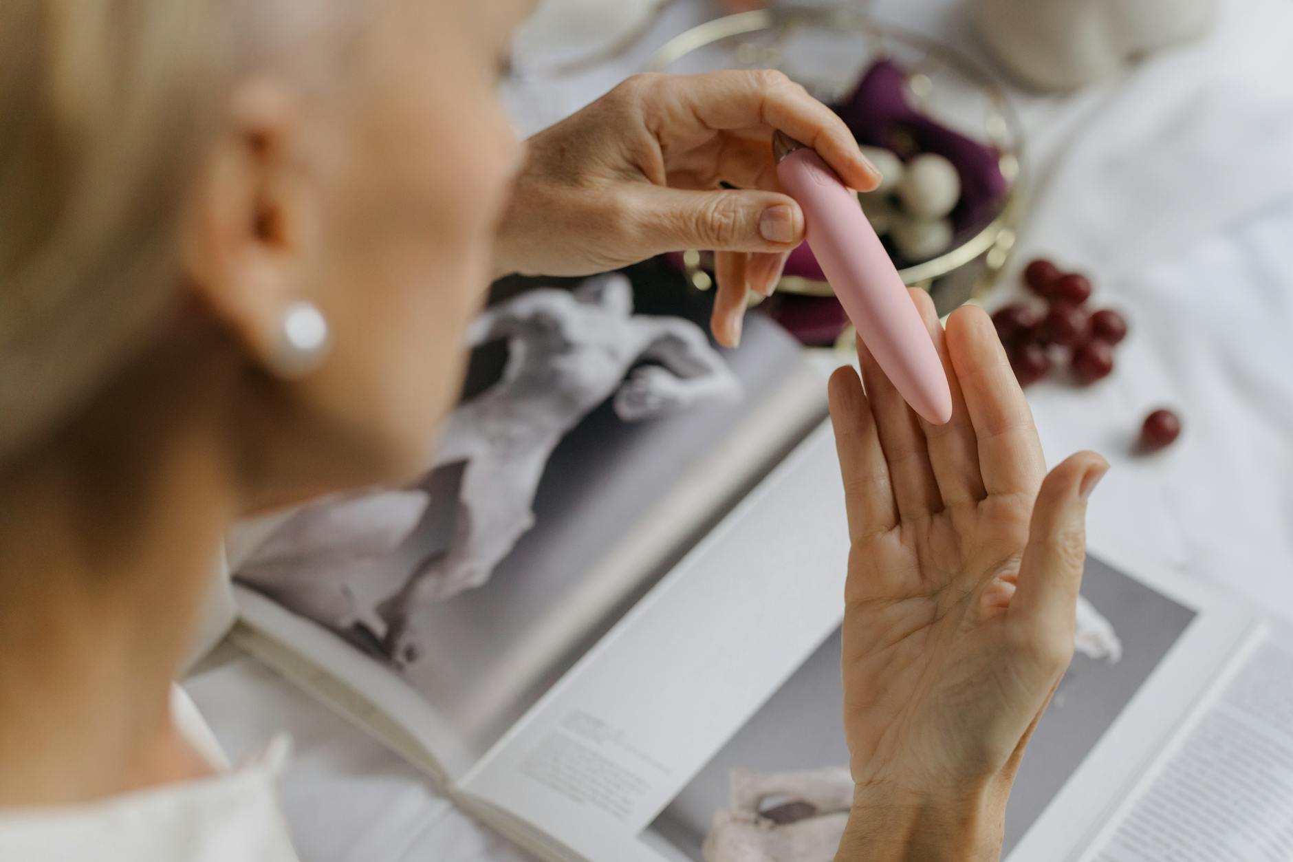 Close-up of a hand holding a pink vibrator against a personal, intimate backdrop