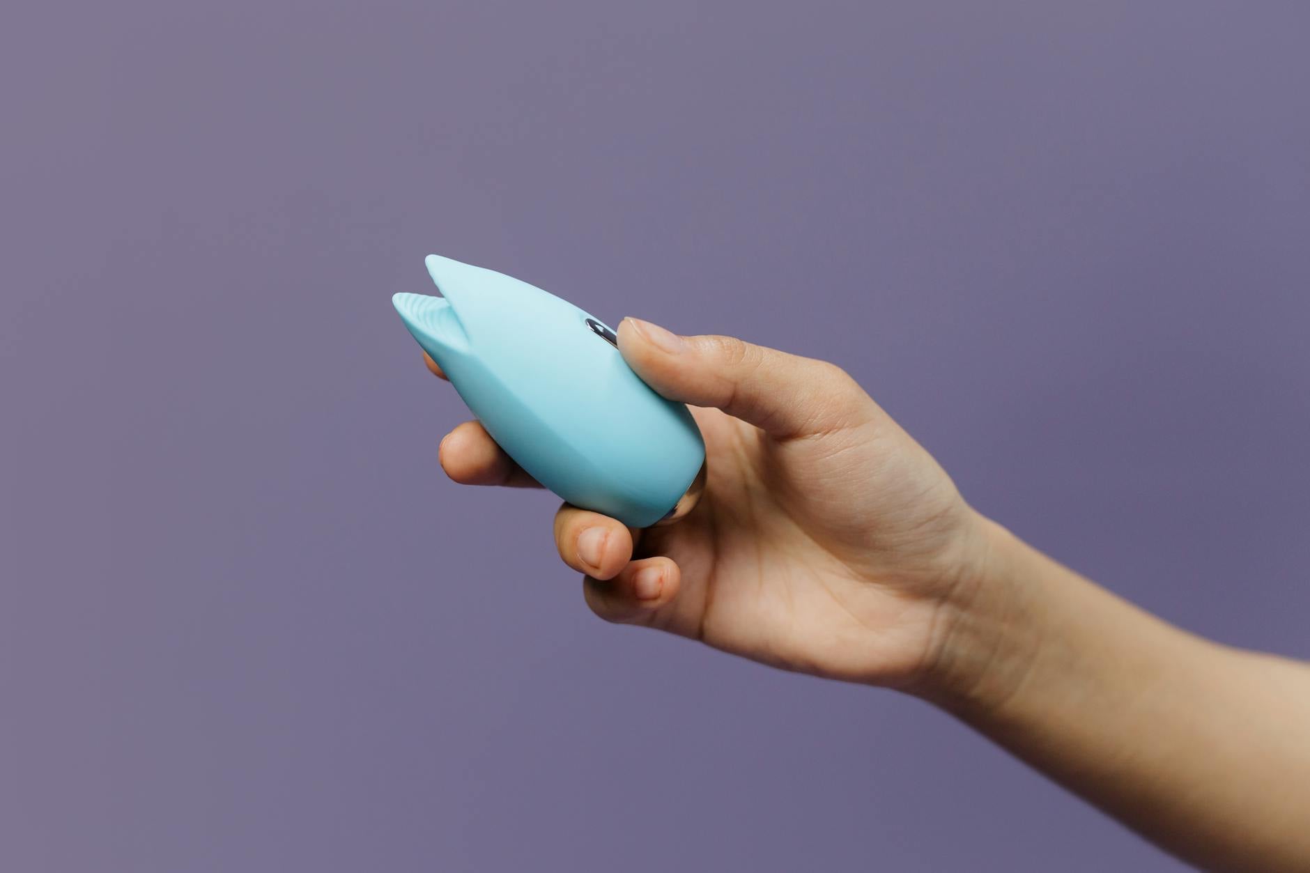 紫色の背景に持たれた青いシリコーン振動器、セルフラブと性への向き合い方を表現