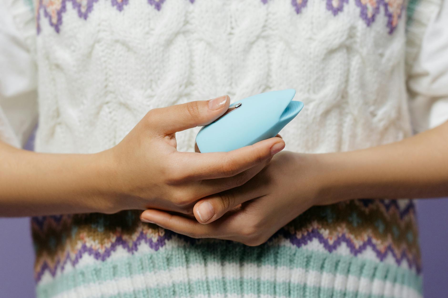 Woman holding a blue vibrator against a knitted sweater, representing gentle reconnection