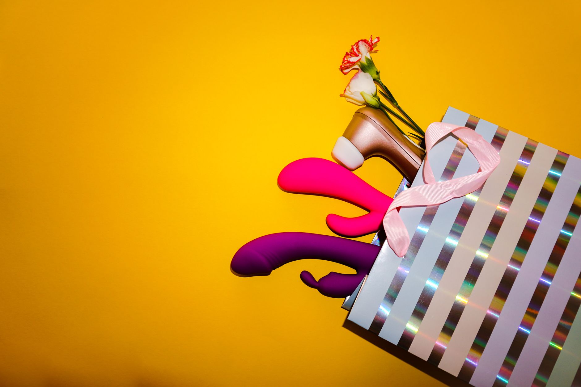 Hand holding an orange vibrator against a purple backdrop, showcasing modern sensuality and intimate self-care