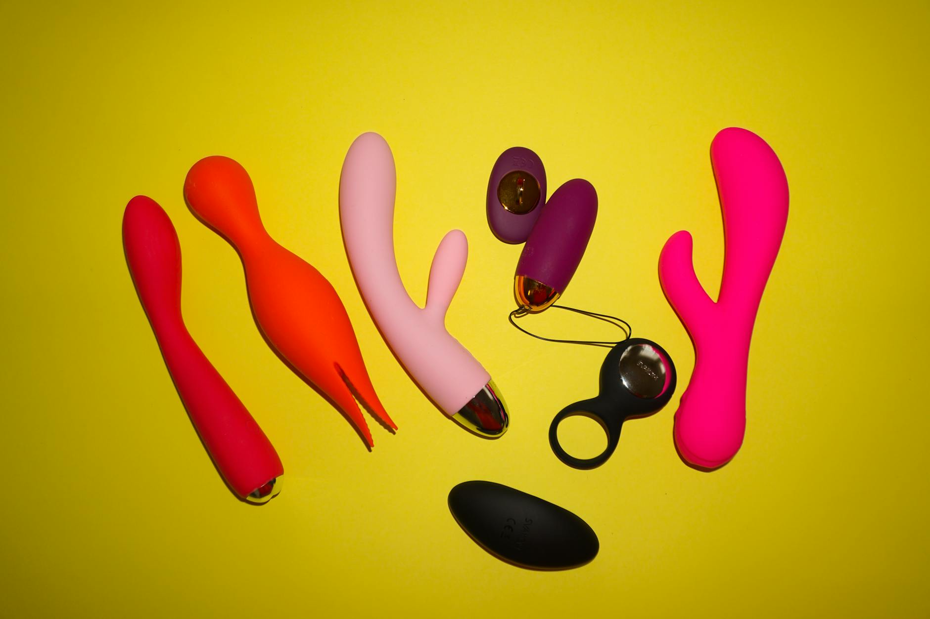 Woman holding colorful vibrators in a thoughtful pose, representing reconnection with pleasure after stopping hormonal birth control